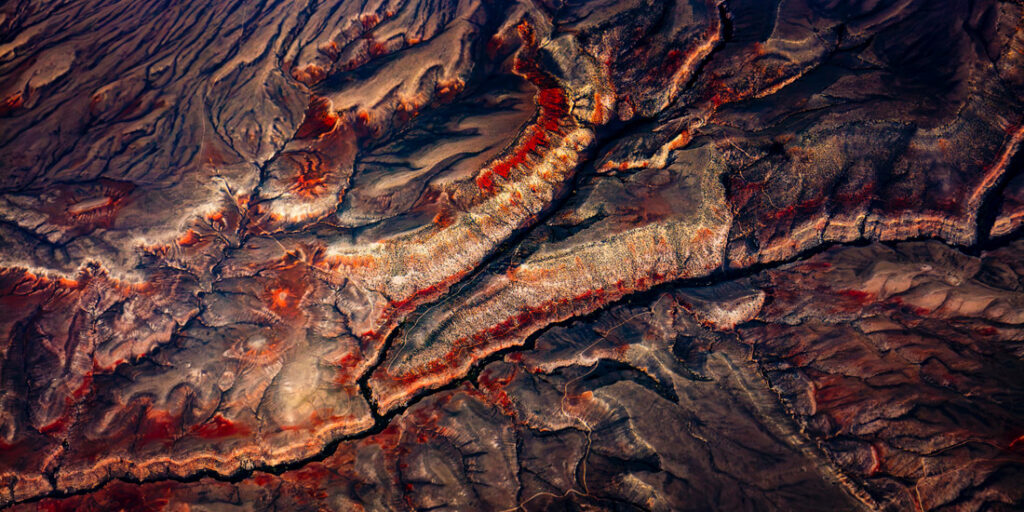 Aerial view of a rugged, colorful canyon landscape with red and orange hues, Montana, United States.